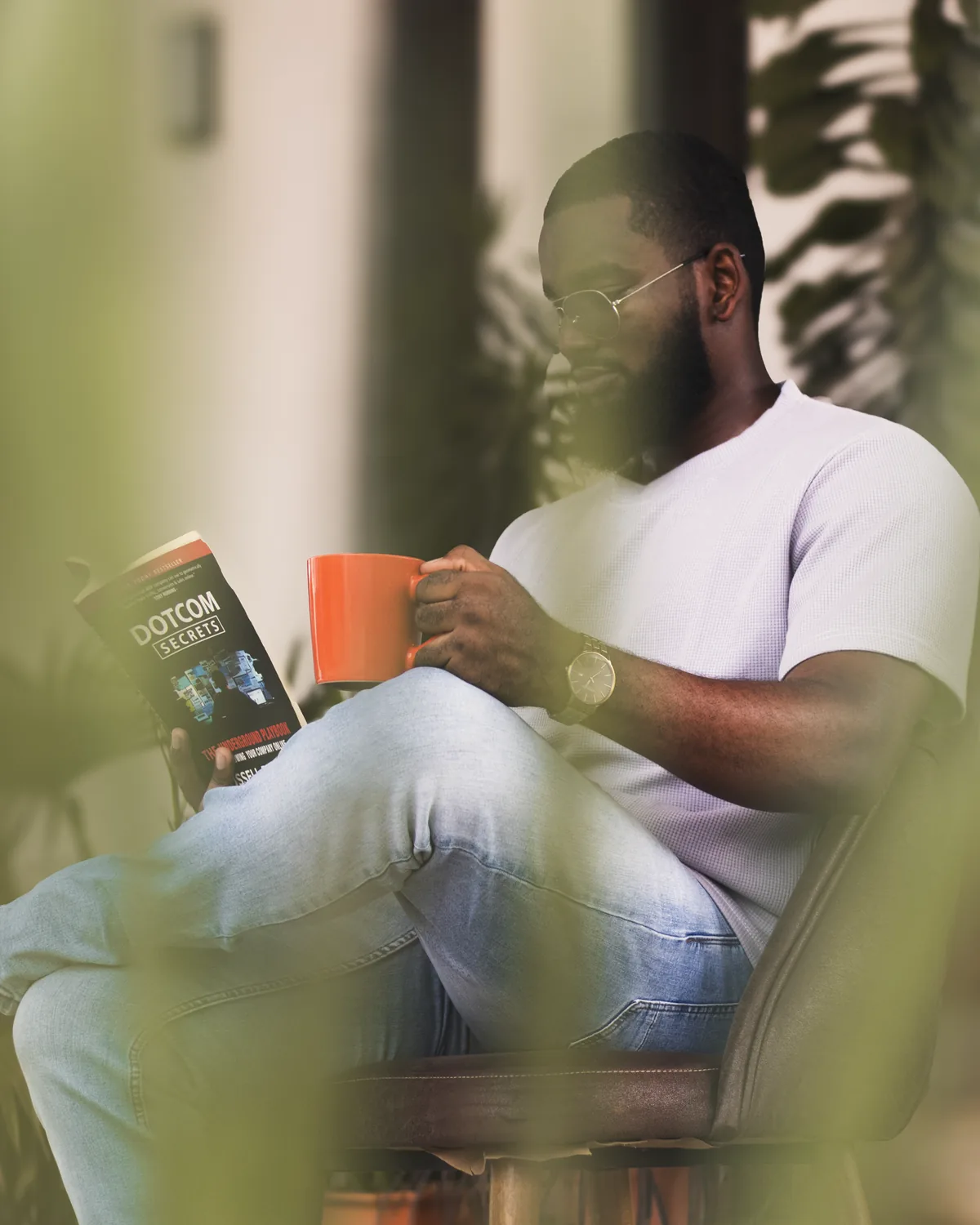 Omar reading a book with a coffee in hand