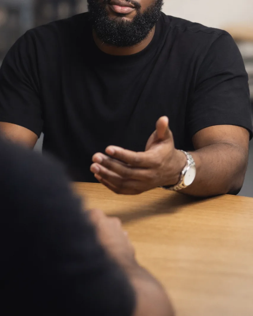 Omar across a table from a client, mid-sentence, hands open