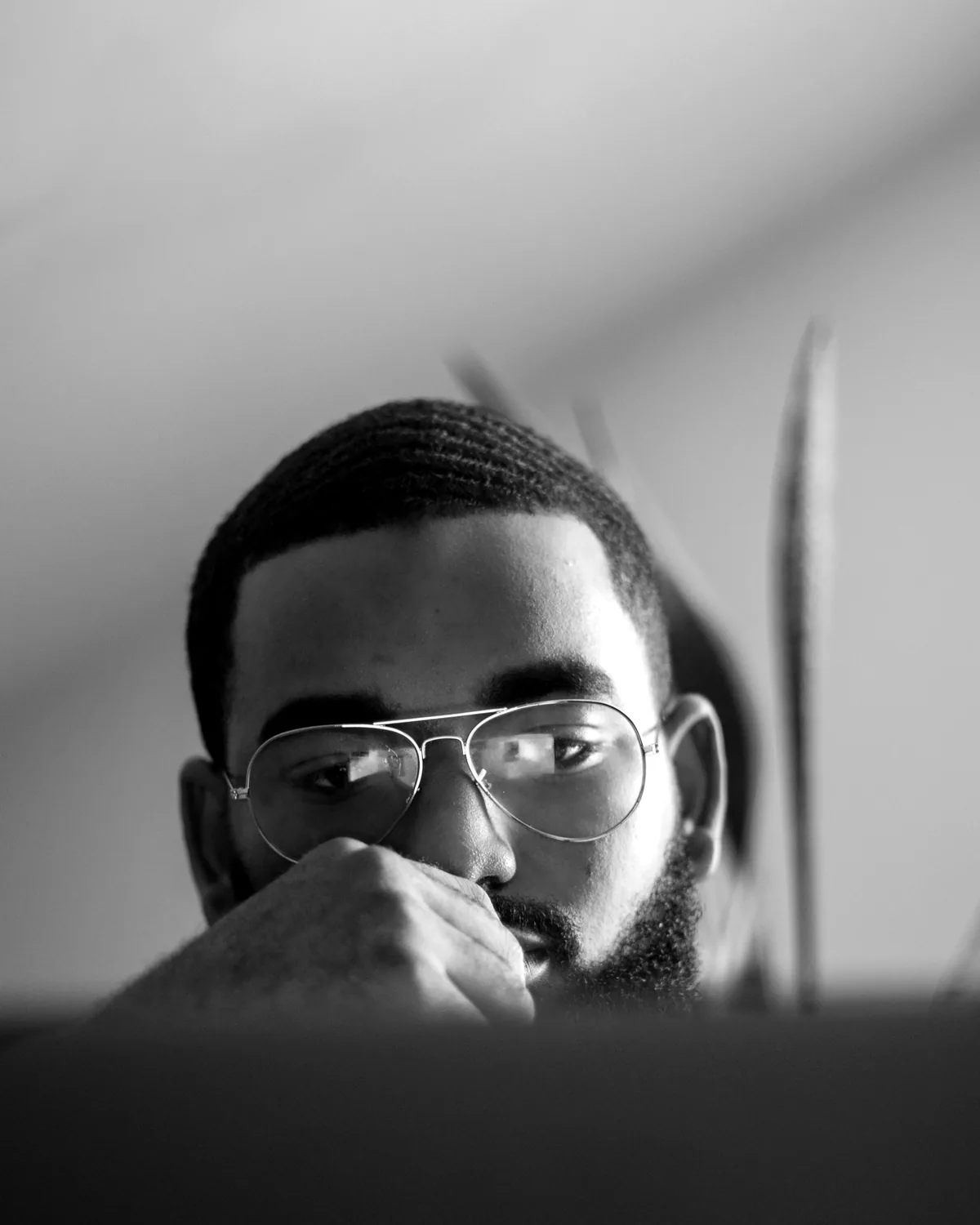 Omar in glasses, hand to his chin, reading something closely