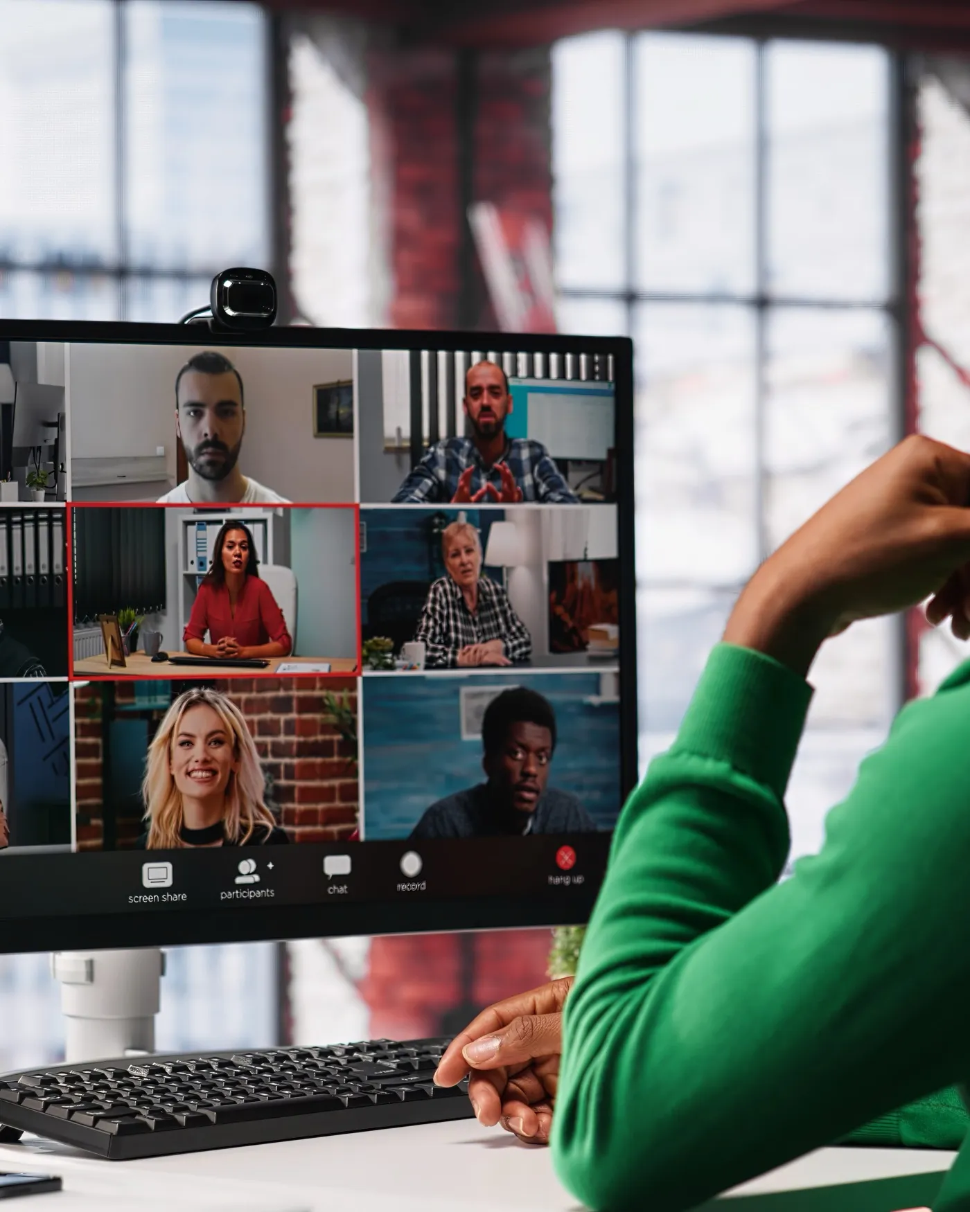 A video call on a laptop screen, with a grid of people on it